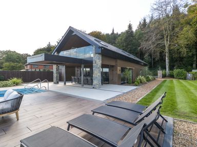 An outdoor area with a pool and loungers at Forest Lodge in Pontyclun