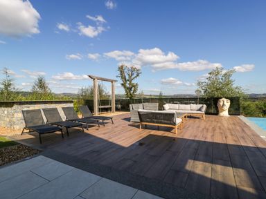 A patio with sun loungers and an outdoor sofa at Forest Lodge in Pontyclun