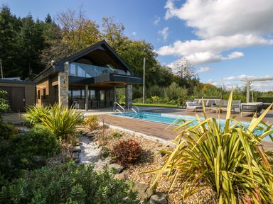 An outdoor area with a swimming pool and deck at Forest Lodge in Pontyclun