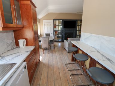 A kitchen with cabinets, countertop, and dining area at The East Wing Apartment in Claremorris