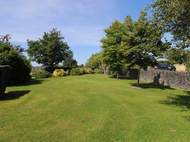 A garden with grass and trees at The East Wing Apartment in Claremorris
