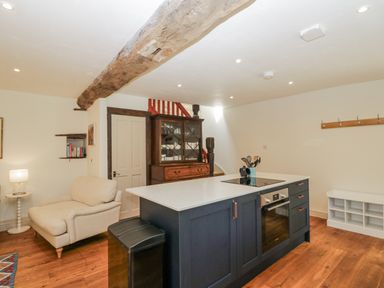 A kitchen with a kitchen island and a sofa at Stable cottage Sopworth near Sherston