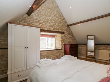 A bedroom with a bed and a wardrobe at Stable cottage Sopworth near Sherston