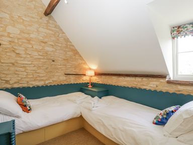 A bedroom with two beds and a lamp at Stable cottage Sopworth near Sherston