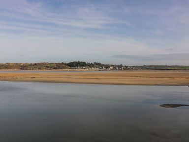 A coastal landscape with water and sandbanks and houses in the distance at 101 Atlantic Bays Holiday Park in Padstow