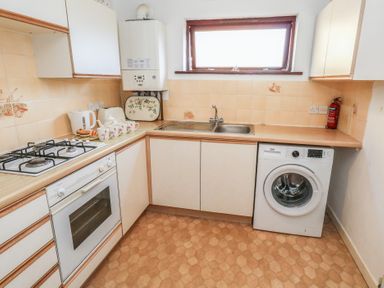 A kitchen with a gas stove and washing machine at Flat 9 in Swanage