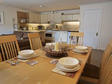 A dining table set with plates and bowls in an open kitchen and living area at 10 Dartmouth House in Dartmouth