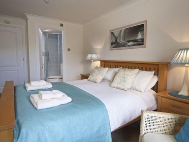 A bedroom with a double bed blue bedspread and pillows two bedside tables with lamps and an ensuite shower at 10 Dartmouth House in Dartmouth