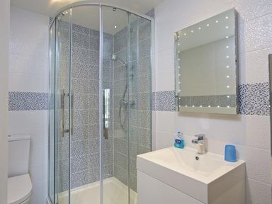 A bathroom with a glass shower enclosure a white sink with a mirror above and a toilet at 10 Dartmouth House in Dartmouth
