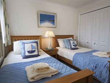 A bedroom with two single beds blue bed covers and boat themed pillows at 10 Dartmouth House in Dartmouth