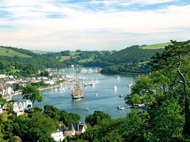 A river with boats docked and houses along the shore surrounded by green hills and trees at 10 Dartmouth House in Dartmouth