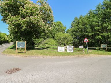 A road with signs for Rosliston Forestry Centre and a wooden fence with trees in the background at Sycamore Lodge in Rosliston