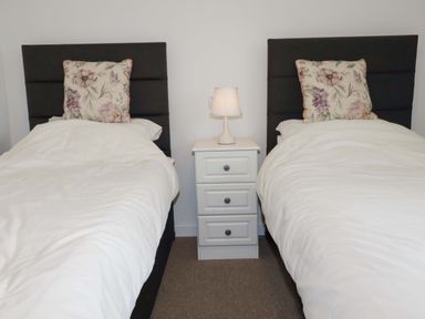 Two single beds with pillows and a nightstand in between at Folly View Cambrose near Illogan