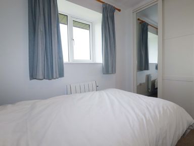 A bedroom with a bed and window at Folly View in Cambrose near Illogan