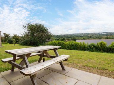 A picnic table on a patio with a view at Folly View in Cambrose near Illogan