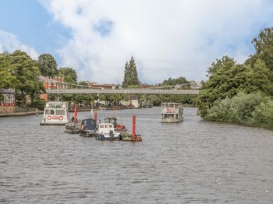 Boats on a river with a bridge in the background at The Garden Hut in Wrexham