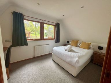 A bedroom with a bed, desk and window at Acorn Lodge Finlakes Holiday Park near Chudleigh