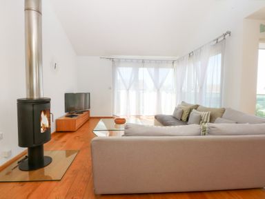 A living room with a wood stove and television at Shearwater in Rhosneigr