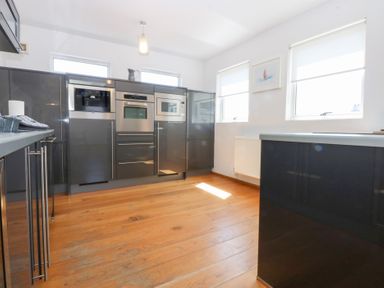 A kitchen with built-in appliances and wooden flooring at Shearwater in Rhosneigr
