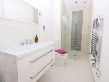 A bathroom with a sink, shower, and toilet at Shearwater, Rhosneigr