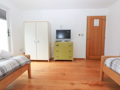A bedroom with two beds and furniture at Shearwater in Rhosneigr