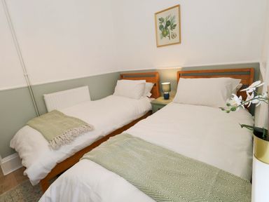 A bedroom with two beds and a bedside table at Seagull & Chips in Weymouth