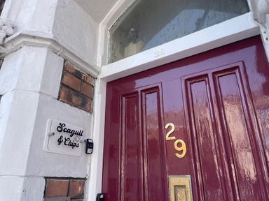An entryway with a maroon door and nameplate at Seagull & Chips in Weymouth
