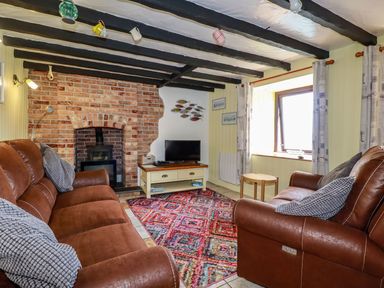 A living room with two brown sofas and a colorful rug in front of a brick fireplace at Rock Cottage in Portmellon near Mevagissey