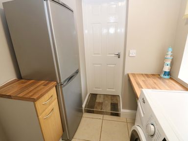 A kitchen with a refrigerator and washing machine at Amblers Rest in Amble