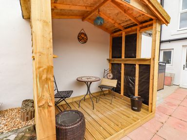 An outdoor seating area with a wooden structure and table at Amblers Rest in Amble