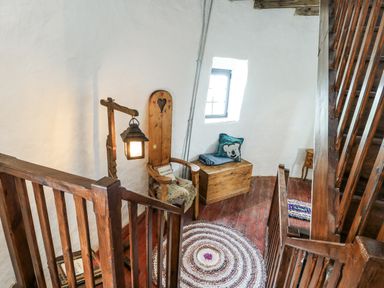 A staircase with a light fixture and wooden chair at The Old Cornmill in Cemaes Bay