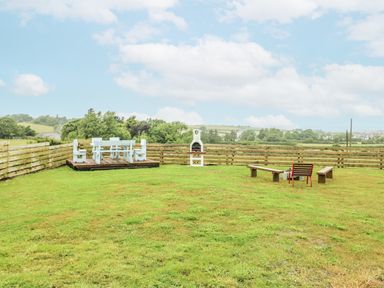 A garden with seating and a grill at The Old Cornmill in Cemaes Bay