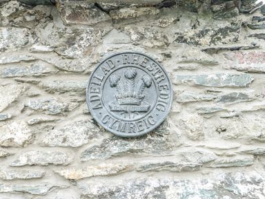 A metal plaque mounted on a stone wall at The Old Cornmill in Cemaes Bay