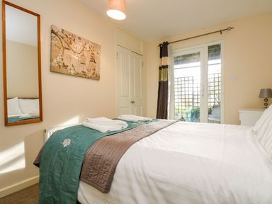 A bedroom with a bed with folded towels on it a mirror on the wall a painting a closet and glass doors at Valley Lodge 31 St Ann's Chapel Cornwall