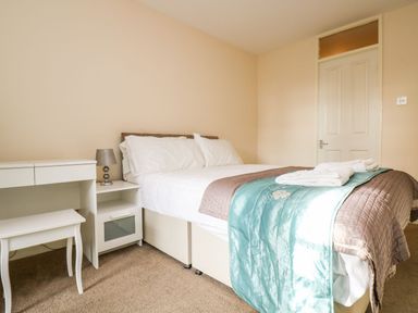 A bedroom with a bed white desk bedside table and lamp at Valley Lodge 31 in St Anns Chapel Cornwall