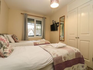 A bedroom with two single beds a wall mounted tv a mirror a window and a closet at Valley Lodge 31 in St Ann's Chapel Cornwall