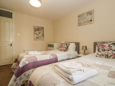 A bedroom with two single beds each with floral pillows and folded towels at Valley Lodge 31 in St Ann's Chapel Cornwall