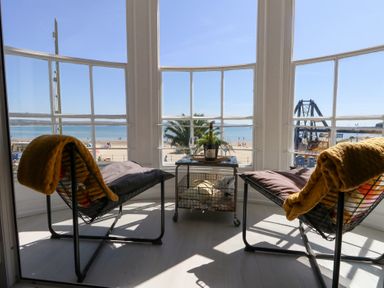 A sunroom with chairs and a table overlooking the beach at The Beach Condo in Weymouth