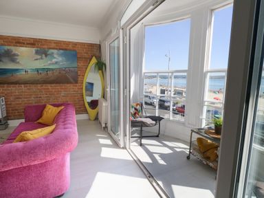 A living room with a pink sofa and sea view at The Beach Condo in Weymouth