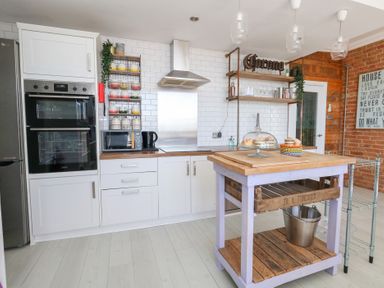 A kitchen with appliances and a wooden island at The Beach Condo in Weymouth
