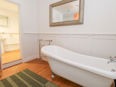 A bathroom with a bathtub and mirror at The Beach Condo in Weymouth