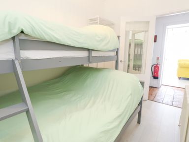 A bedroom with a bunk bed and green bedding at The Beach Condo in Weymouth