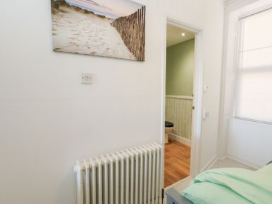 A bedroom with a radiator and a door leading to a toilet at The Beach Condo in Weymouth