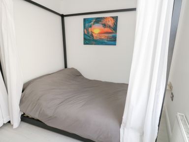 A bedroom with a canopy bed and painting on the wall at The Beach Condo in Weymouth