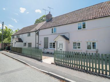 A house with a picket fence and pathway at Old Farm Cottage in Warminster