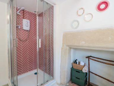 A shower with glass doors and decorative items at Old Farm Cottage in Warminster