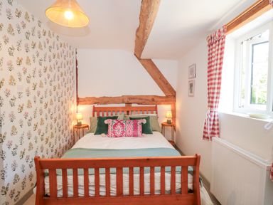 A bedroom with a bed and floral wallpaper at Old Farm Cottage in Warminster