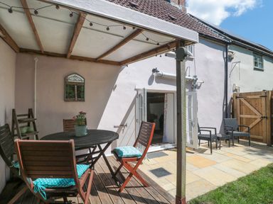 An outdoor patio with a table and chairs at Old Farm Cottage in Warminster