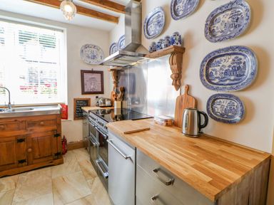 A kitchen with wooden countertops blue patterned plates on the wall and appliances at Shaftoe Mews in Haydon Bridge