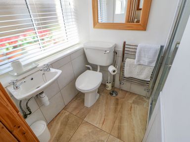 A small bathroom with a toilet sink towel rack and mirror at Shaftoe Mews in Haydon Bridge